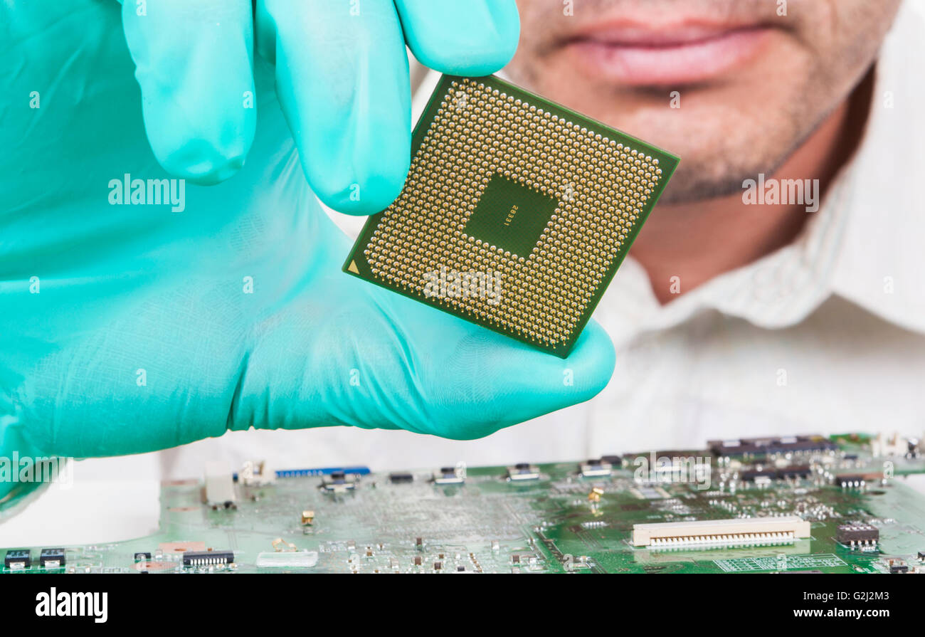 Verifying closely microprocessor held in hand with gloves Stock Photo