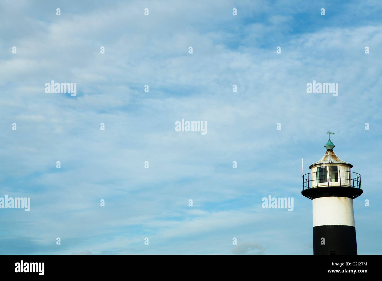 Top of the lighthouse (lantern cabin) framed to the right and against a blue yet cloudy sky. Portsmouth. Stock Photo