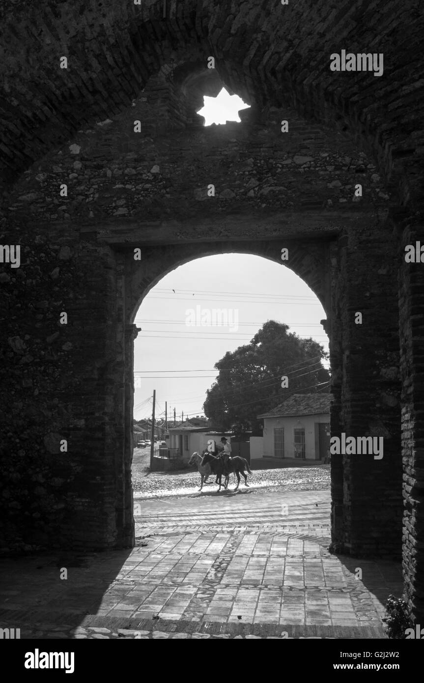 Santa Ana ruins framing two horse riders passing by. Santa Ana Church, Santa Ana Square, Trinidad, Cuba. Stock Photo