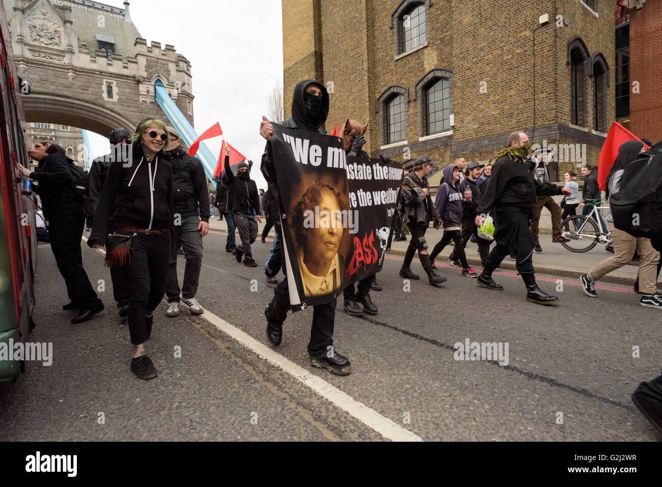 May Day Anarchist group with hidden faces, slogans and red flags walking across Tower Bridge May 1st 2016 Stock Photo