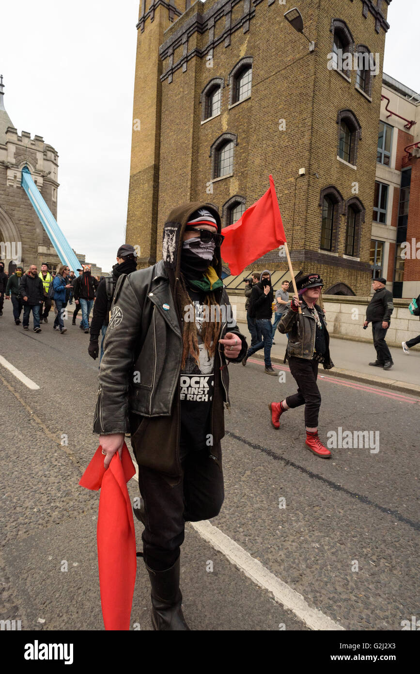 May Day Anarchist group with hidden faces, slogans and red flags walking across Tower Bridge May 1st 2016 Stock Photo