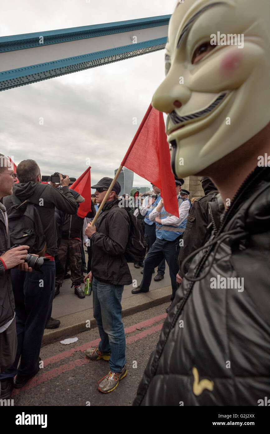 May Day Anarchist group with hidden faces, slogans and red flags walking across Tower Bridge May 1st 2016 Stock Photo
