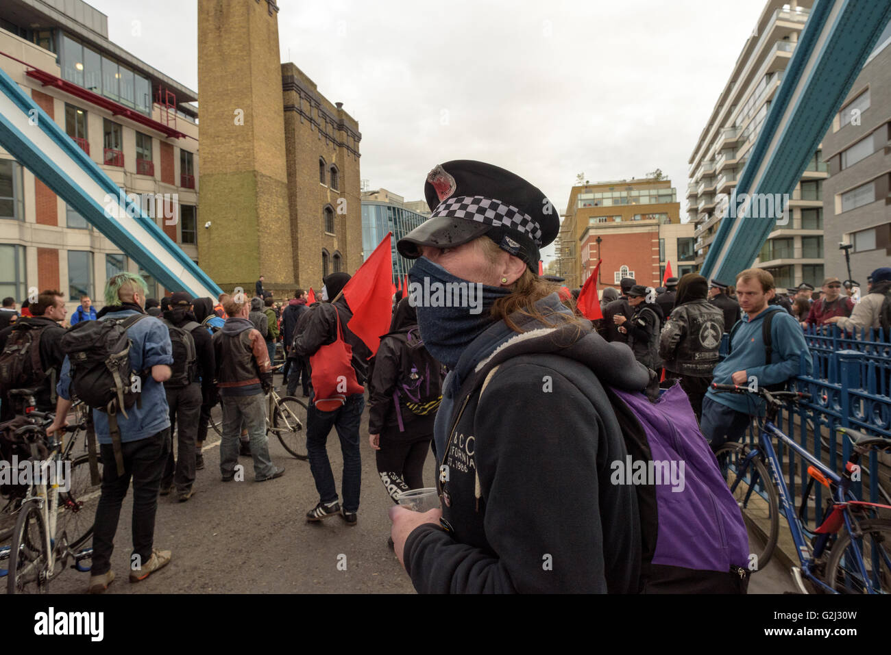 May Day Anarchist group with hidden faces, slogans and red flags walking across Tower Bridge May 1st 2016 Stock Photo