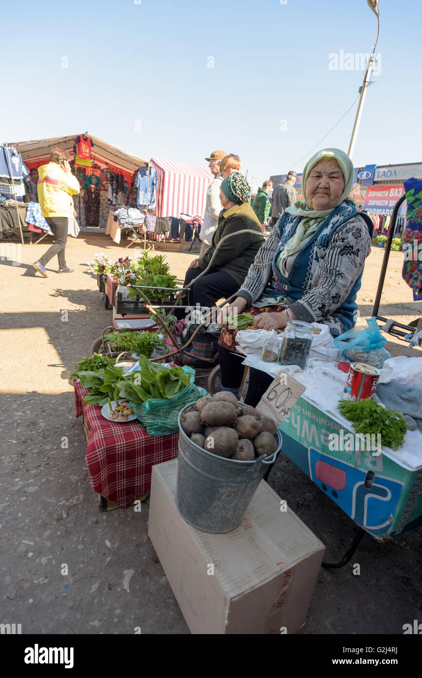 An elderly Russian grandmother sells home grown organic produce from her garden to members of the public at a local fair Stock Photo