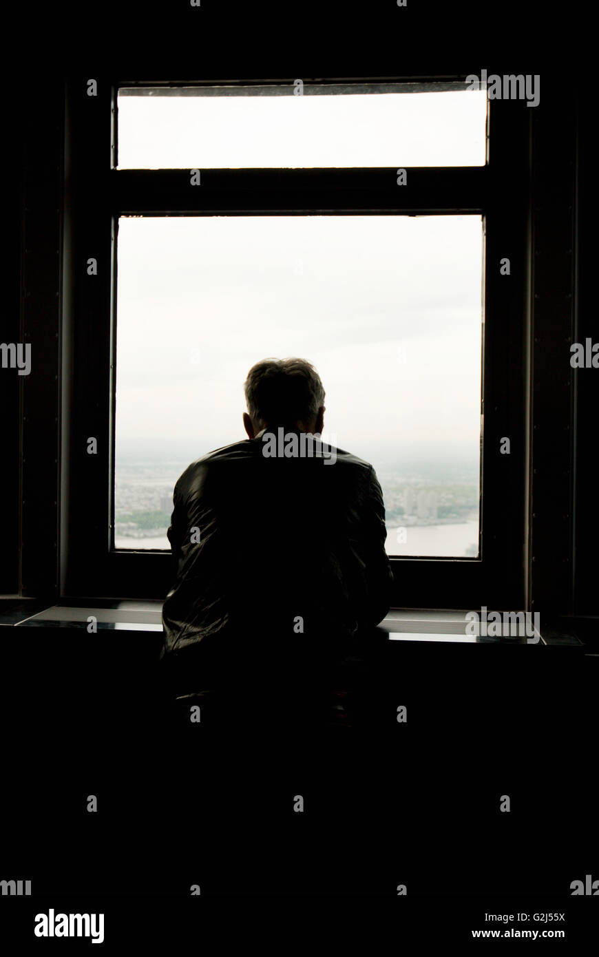 Silhouetted Man Looking Out Window Stock Photo