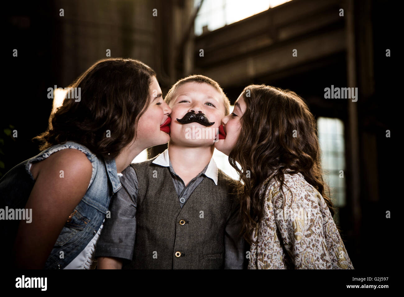 Two Girls Kissing Boy with Wax Lips in Abandoned Warehouse Stock Photo