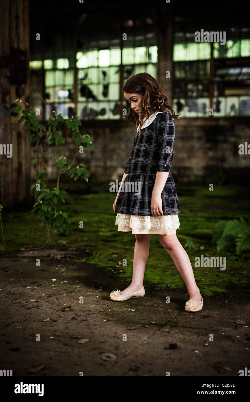 Young Girl Looking Down in Abandoned Warehouse, Portrait Stock Photo