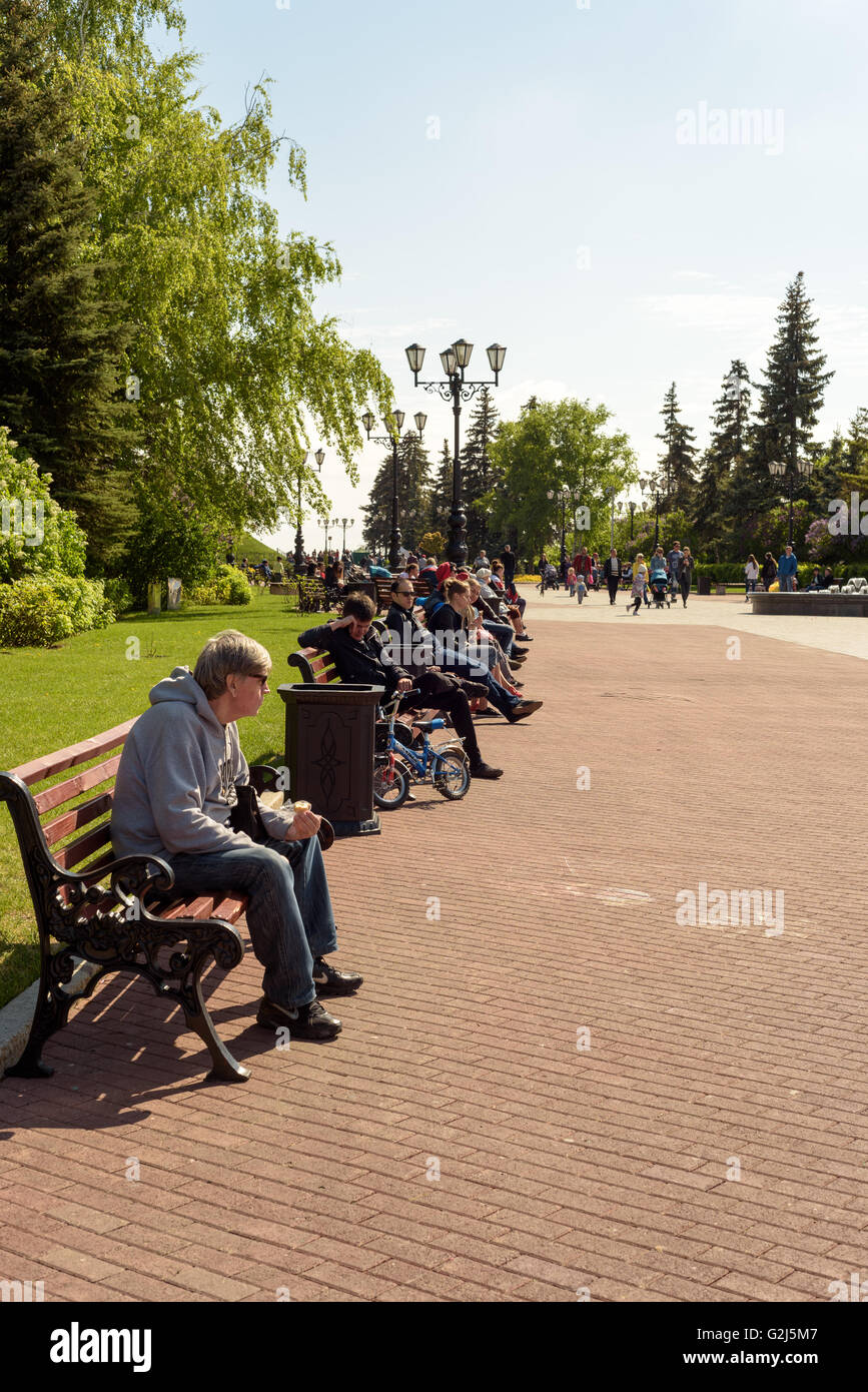 People sitting down enjoying sunshine in the summer sunlight Stock Photo