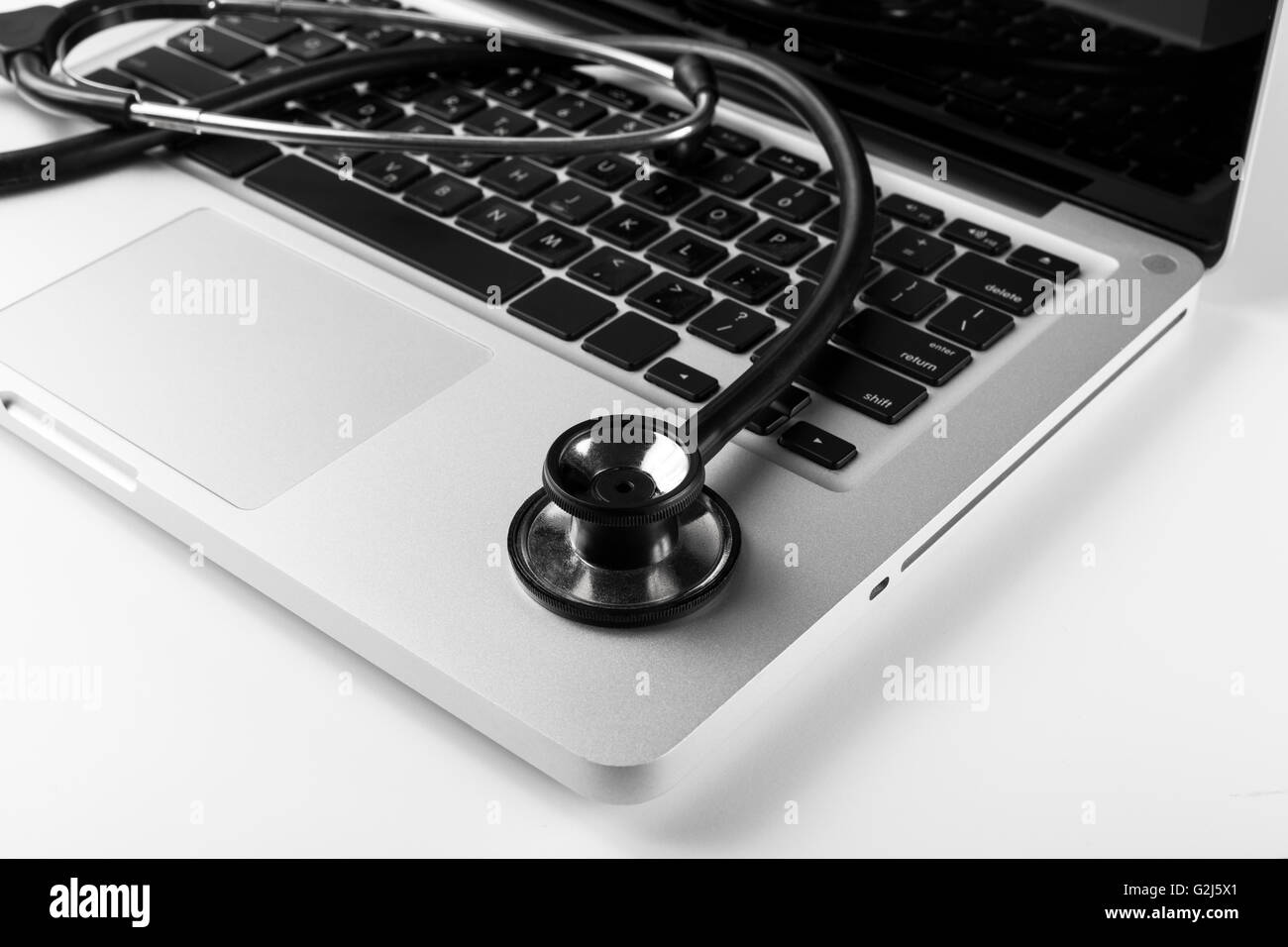 Silver laptop with black stethoscope on the keyboard side Stock Photo