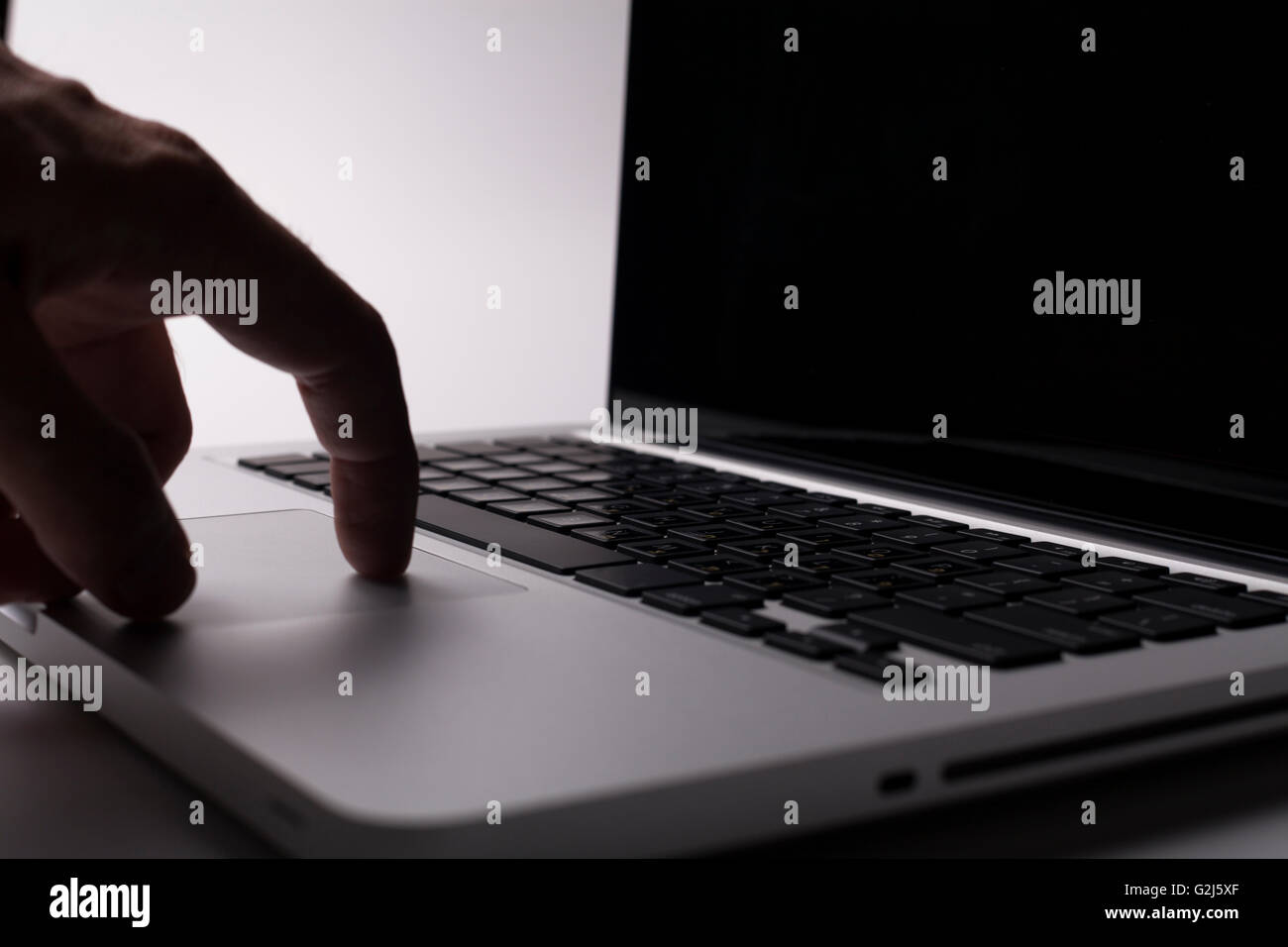 Silver laptop with hand on the trackpad Stock Photo