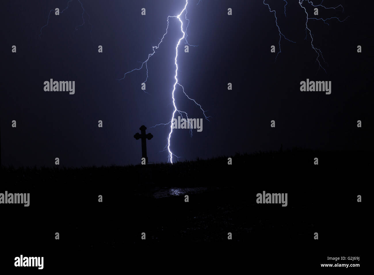 Lightning in a storm with a cross and reflection of the lightning Stock Photo