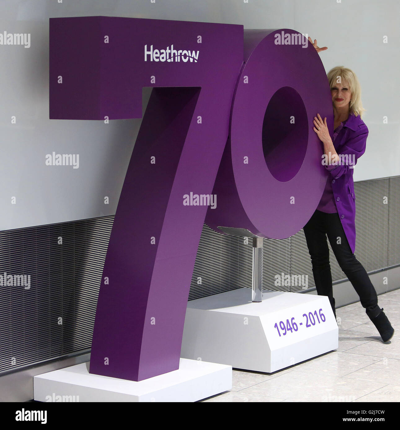 Joanna Lumley poses by one of a series plaques which each represent 'an iconic moment of British culture' from the past seven decades, on the concourse at Terminal 5, Heathrow Airport, to mark the airport's 70th anniversary. Stock Photo