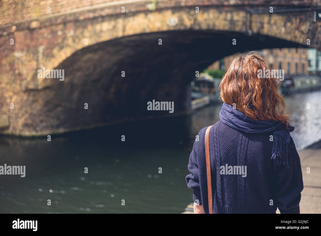 A young woman is walking along a canal near a bridge Stock Photo - Alamy