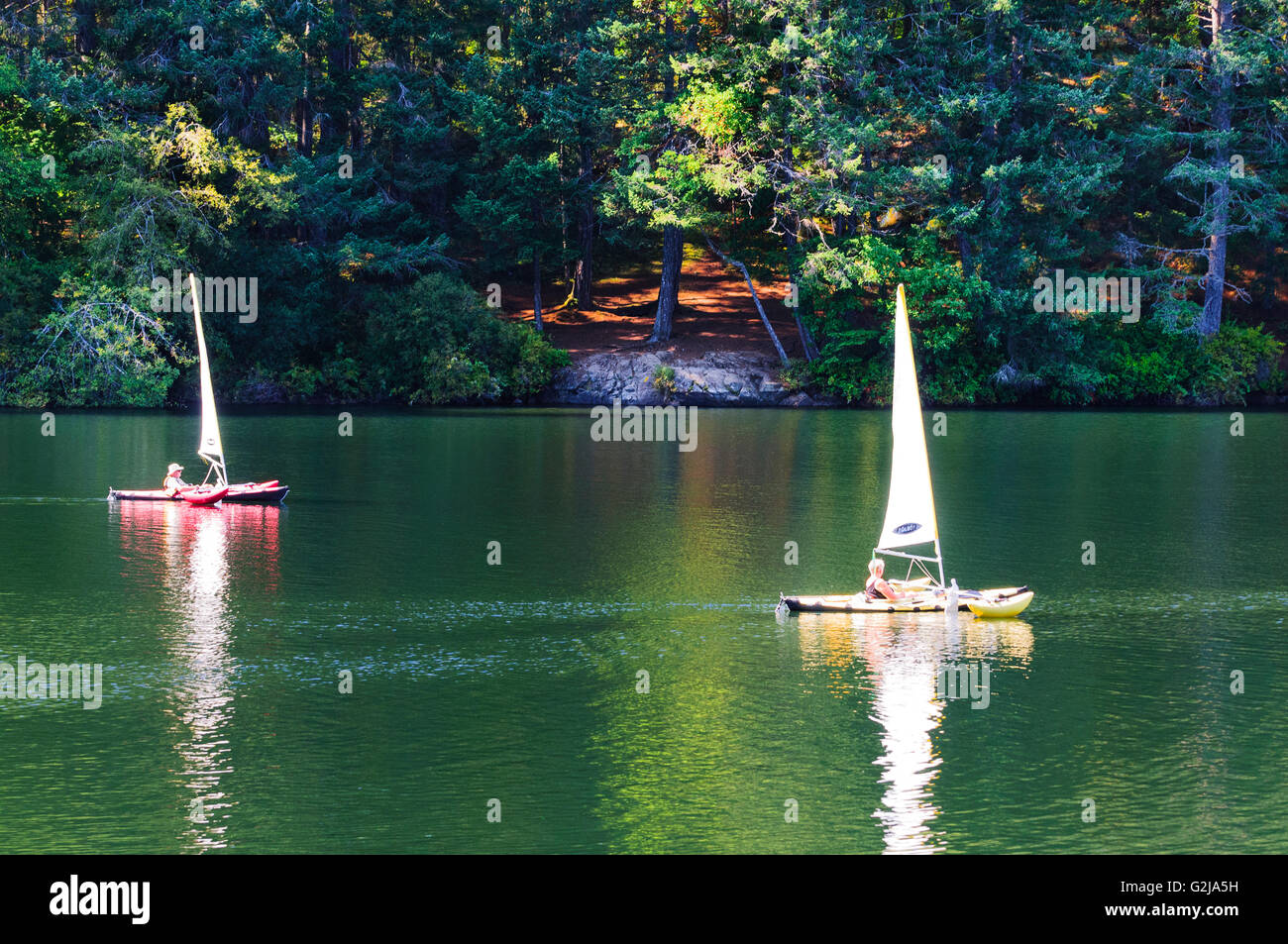 Two kayaks with sails and outriggers on Thetis Lake in Thetis Lake Regional Park in Victoria, British Columbia. Stock Photo