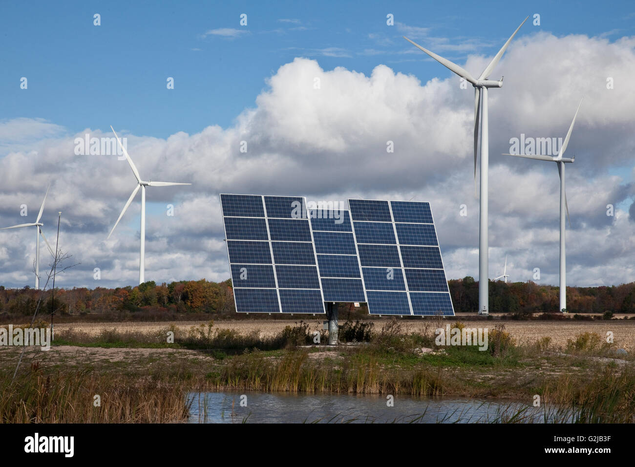 Solar panels on tracking system and windmills in farmland of southwestern Ontario (near Lake Erie), Ontario, Canada. Stock Photo