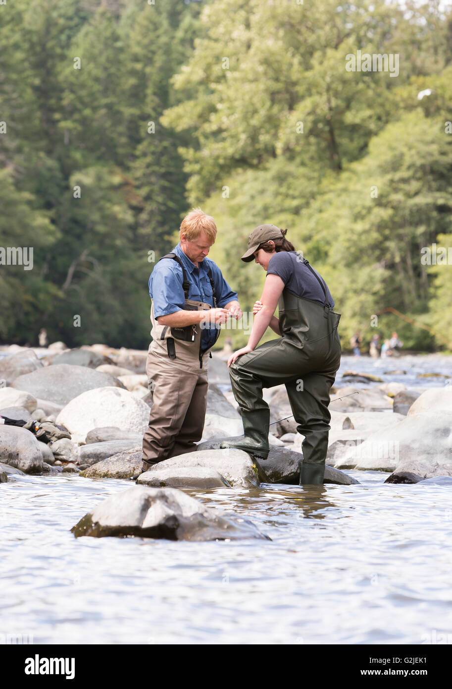 A father ties his sons lure while fishing on the Campbell River.  Campbell River, Vancouver Island, British Columbia, Canada. Stock Photo