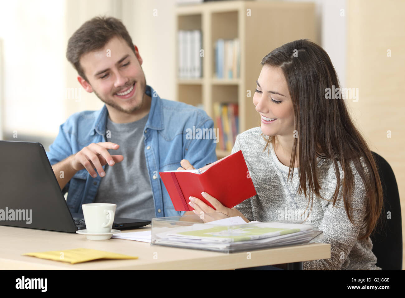 Two entrepreneurs working and taking notes together in table of a little office Stock Photo