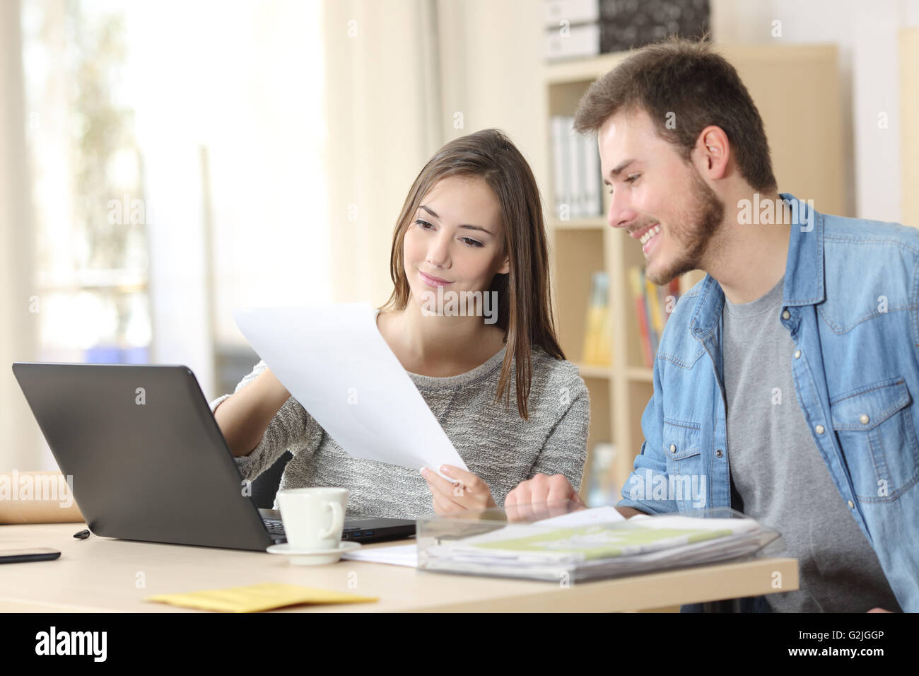 Two entrepreneurs sitting together working in an office desk comparing documents Stock Photo