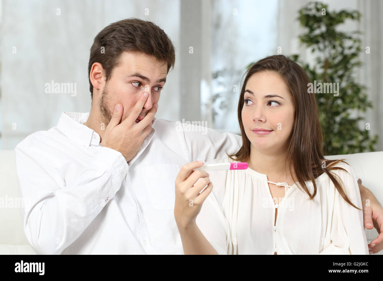 Worried couple or marriage looking each other making a pregnancy test at home. Contraceptive failure concept Stock Photo