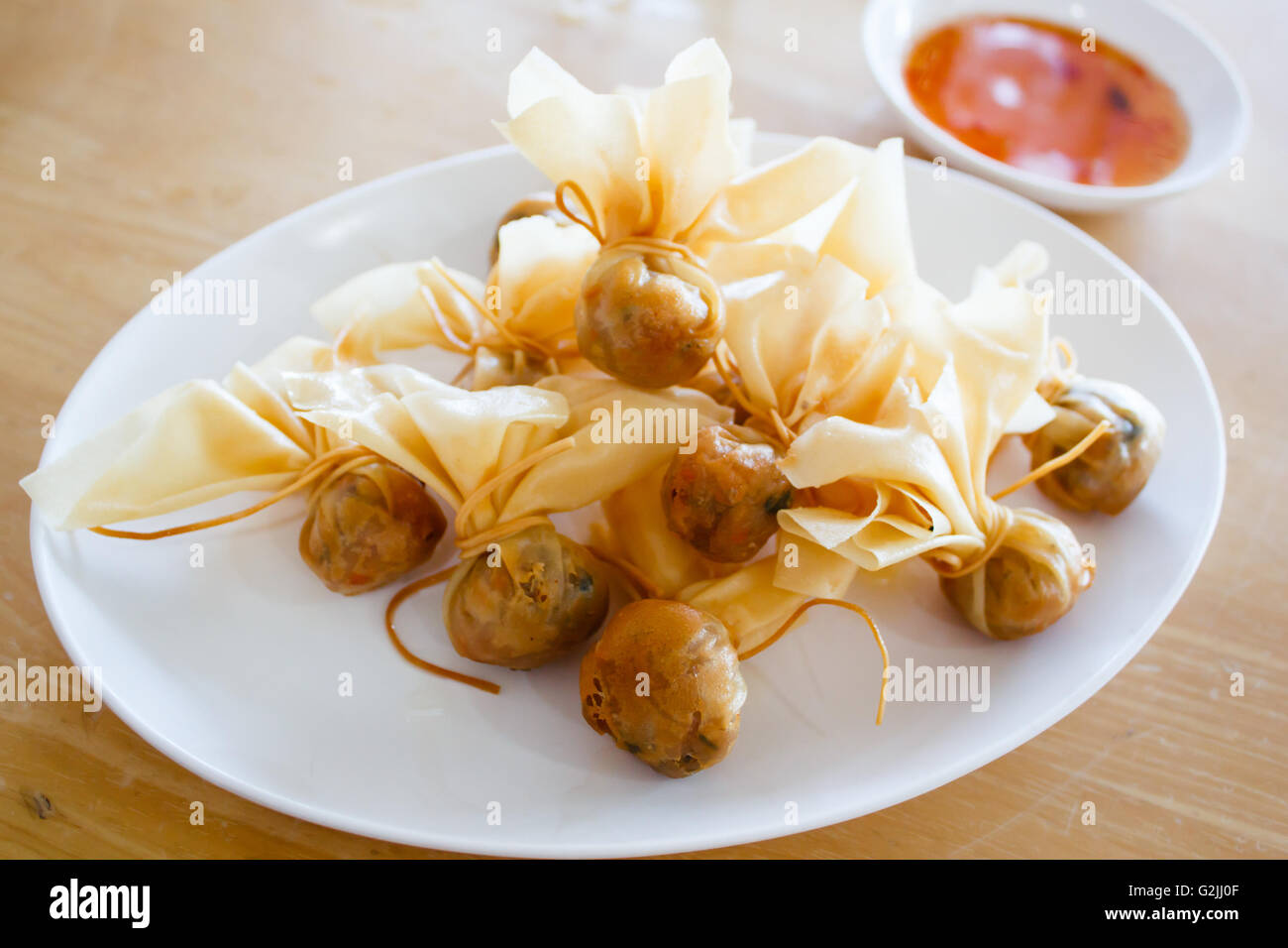 Thai traditional appetisers (Toong Tong), spring rolls served with sweet chilli sauce. Stock Photo