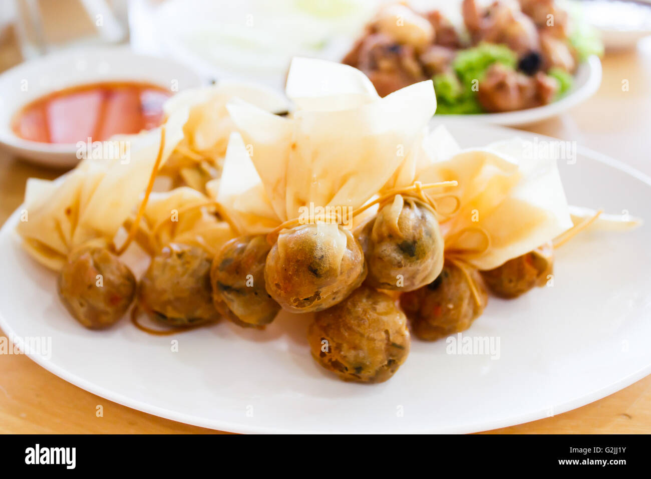 Thai traditional appetisers (Toong Tong), spring rolls served with sweet chilli sauce. Stock Photo