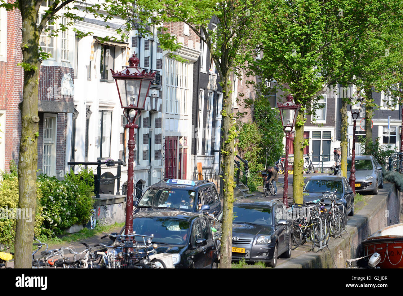Residential area with parked cars and bikes alongside canal. Stock Photo