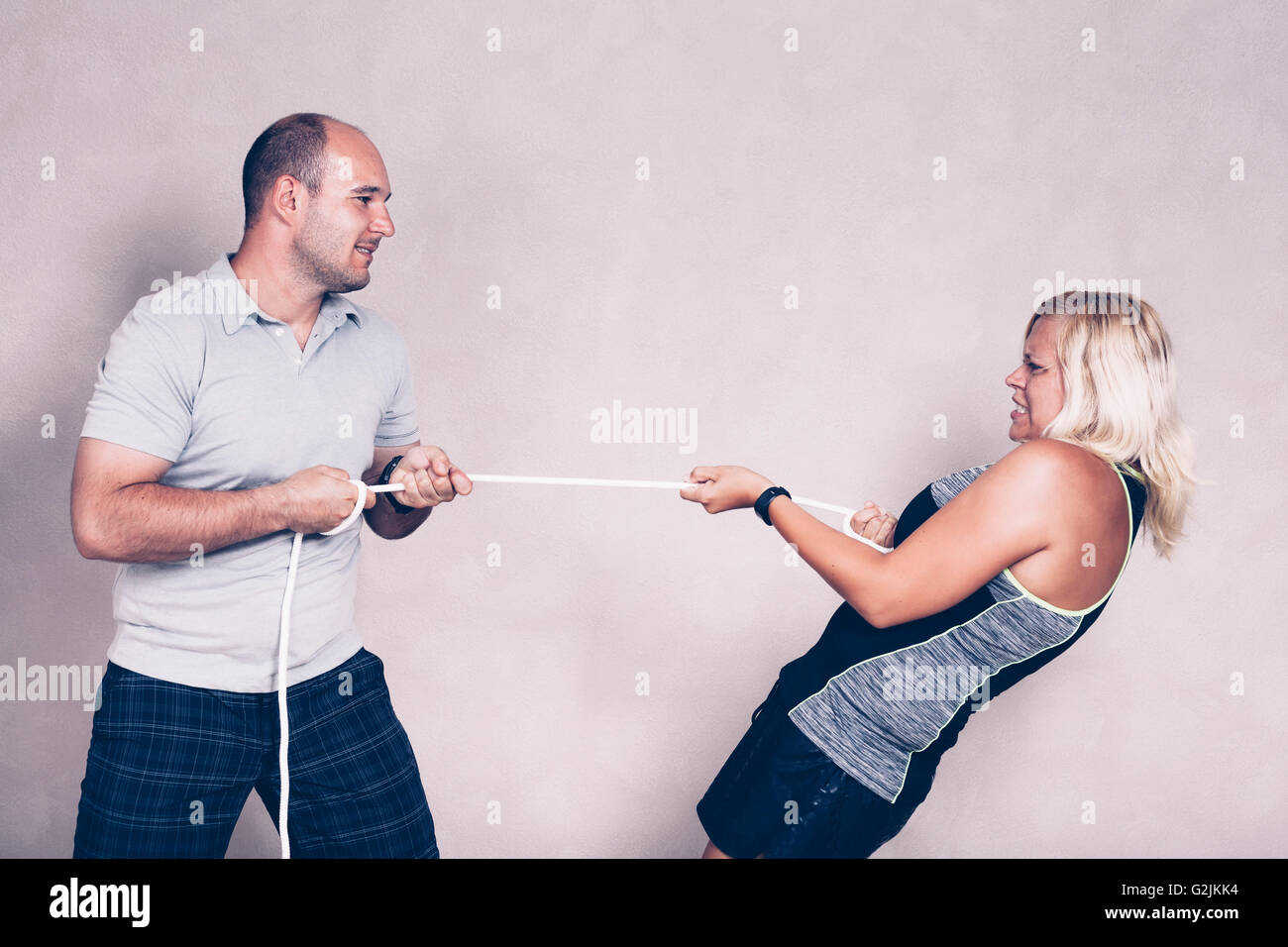 Man and determined sporty woman pulling a rope. Competition, determination and effort concept. Stock Photo
