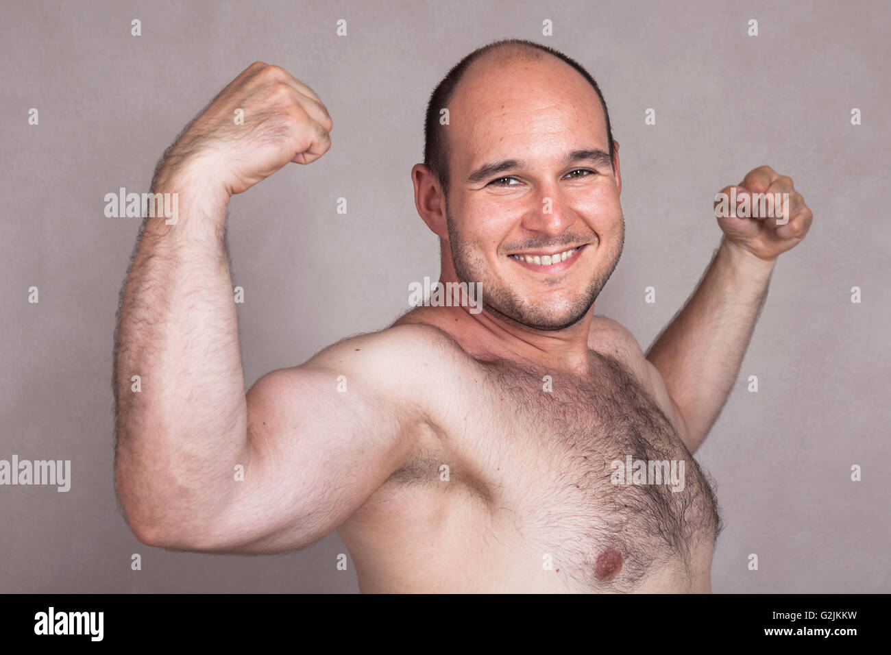 Closeup of happy shirtless man showing his strong arms and muscles. Stock Photo