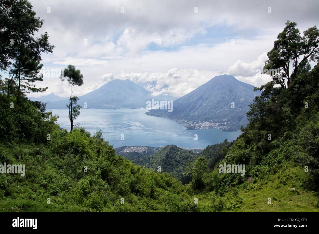 Volcanoes tower over the beautiful sacred Lake Atitlan in Guatemala with Mayan villages nestled in its banks. Stock Photo