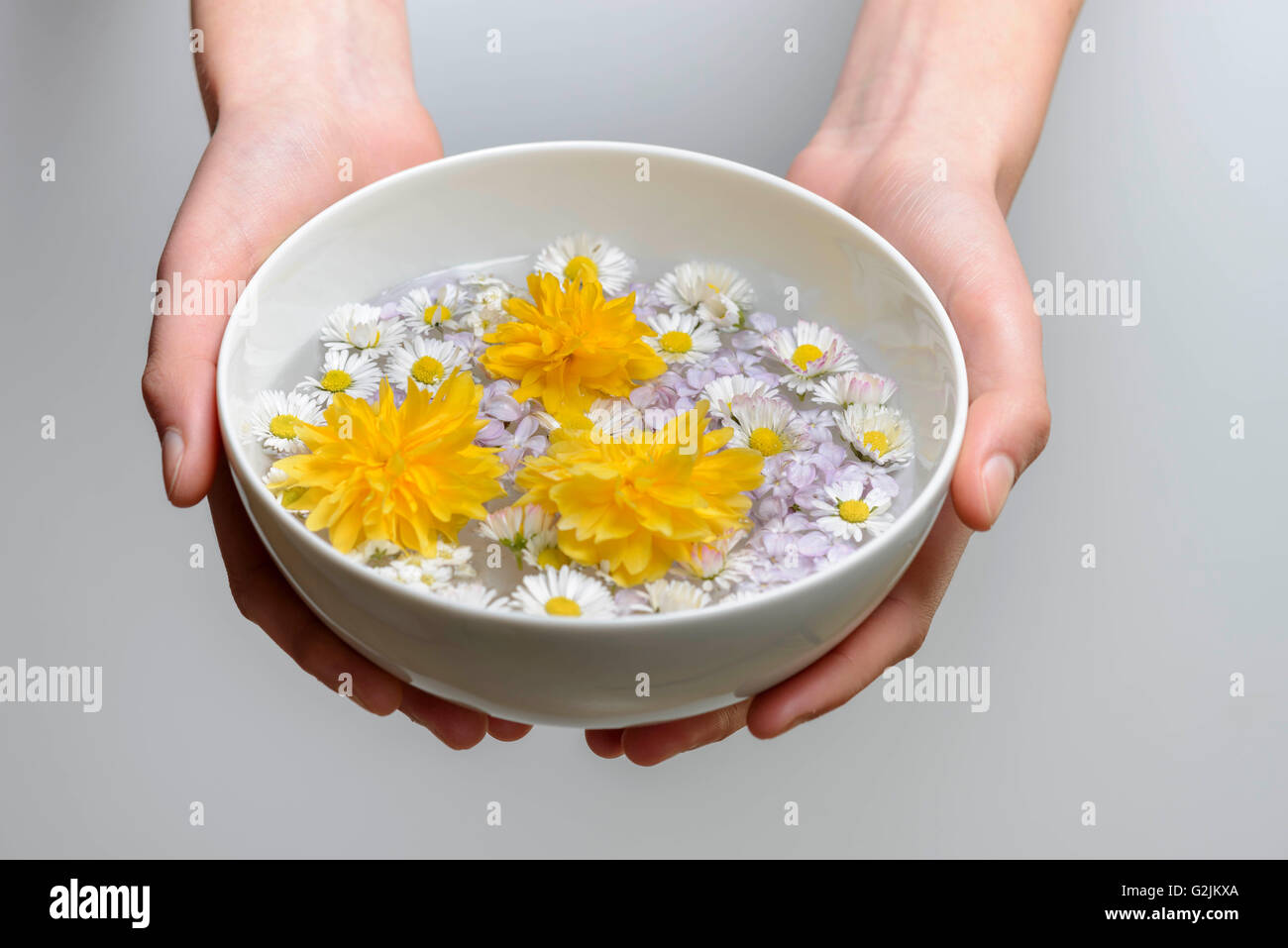 Woman holds  scented bowl with flower petal Stock Photo