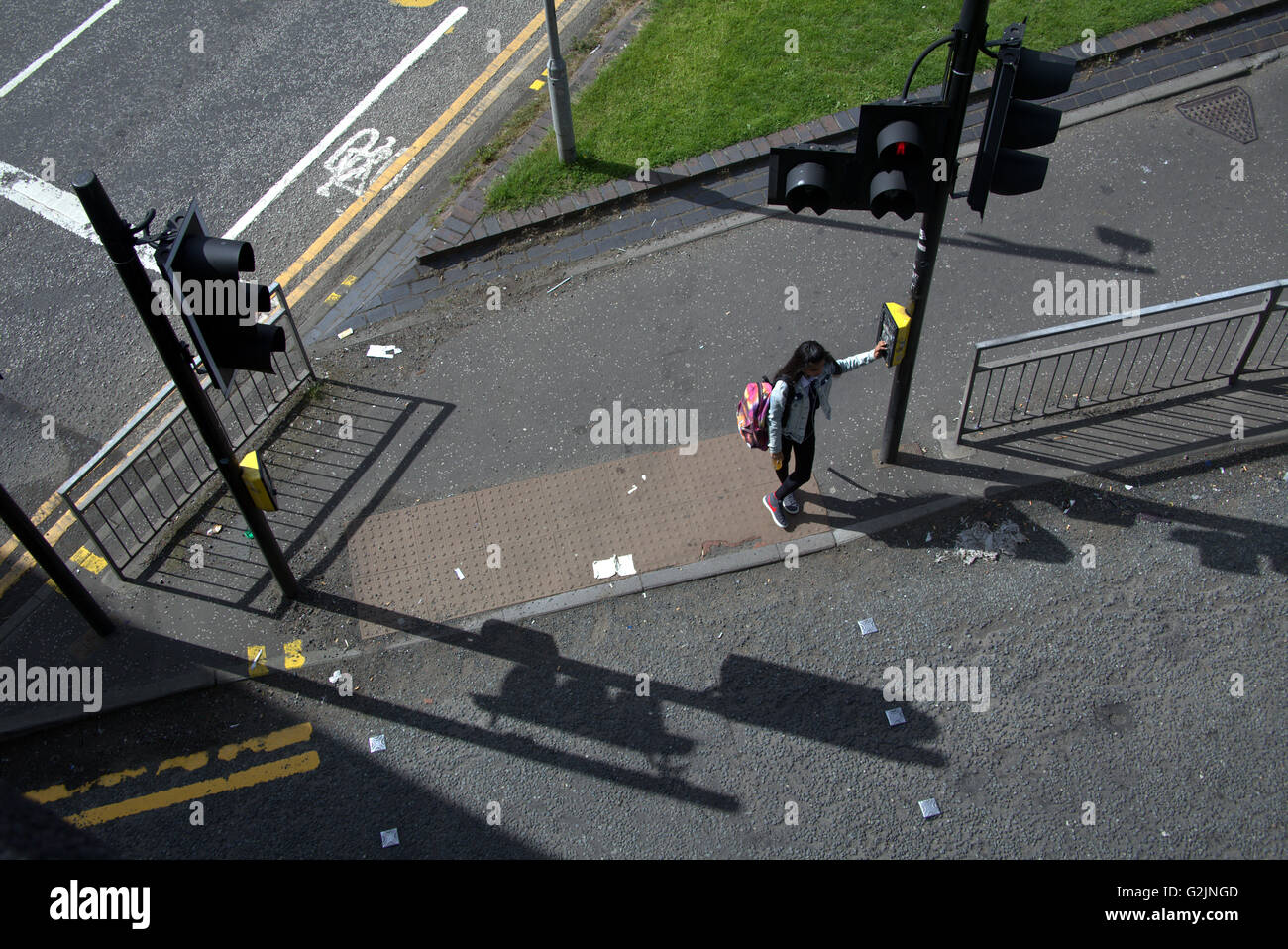 Young girl schoolgirl crosses road from above at traffic lights, Glasgow, Scotland, UK. Stock Photo