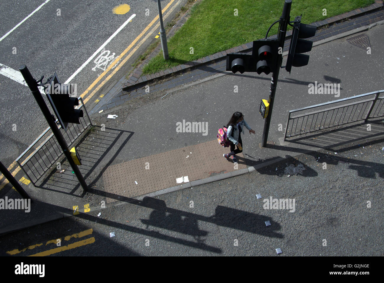 Young girl schoolgirl dances and crosses road from above at traffic lights, Glasgow, Scotland, UK. Stock Photo