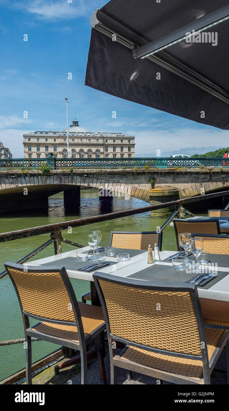 Bistro terrace next to Pont Mayou bridge over Le Nive river with Hotel de ville  (City Hall) of Bayonne, called Mairie. France. Stock Photo