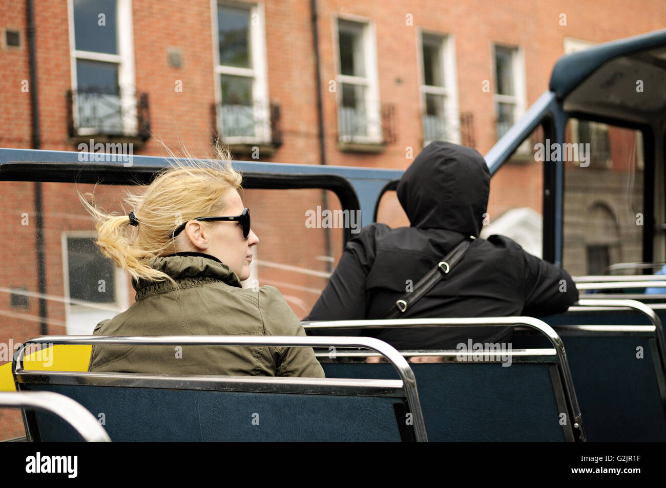 Young blond woman sitting on an open top bus in Dublin, Ireland Stock Photo
