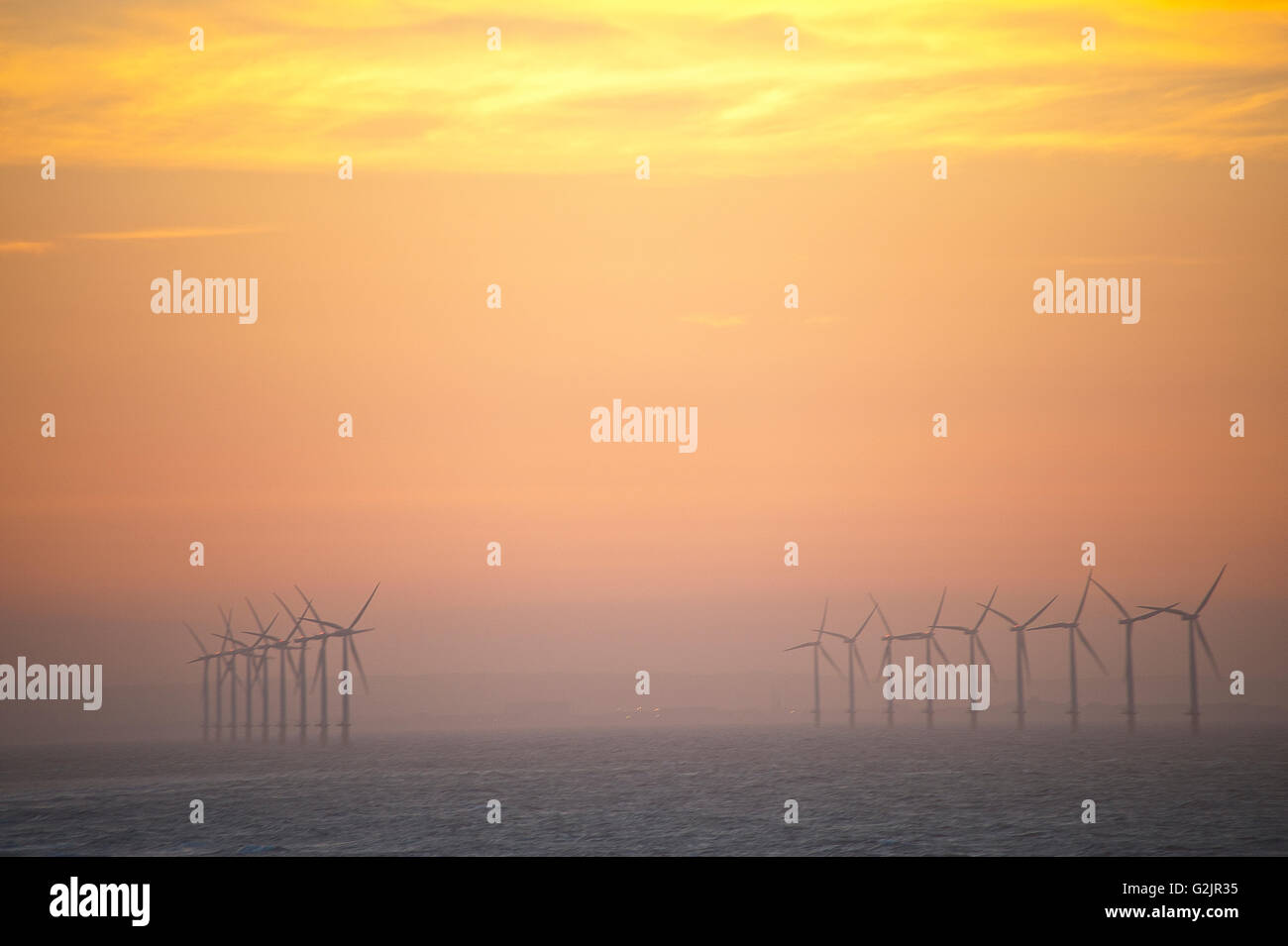 wind turbines at redcar beach producing green renewable energy in sea at sunset Stock Photo