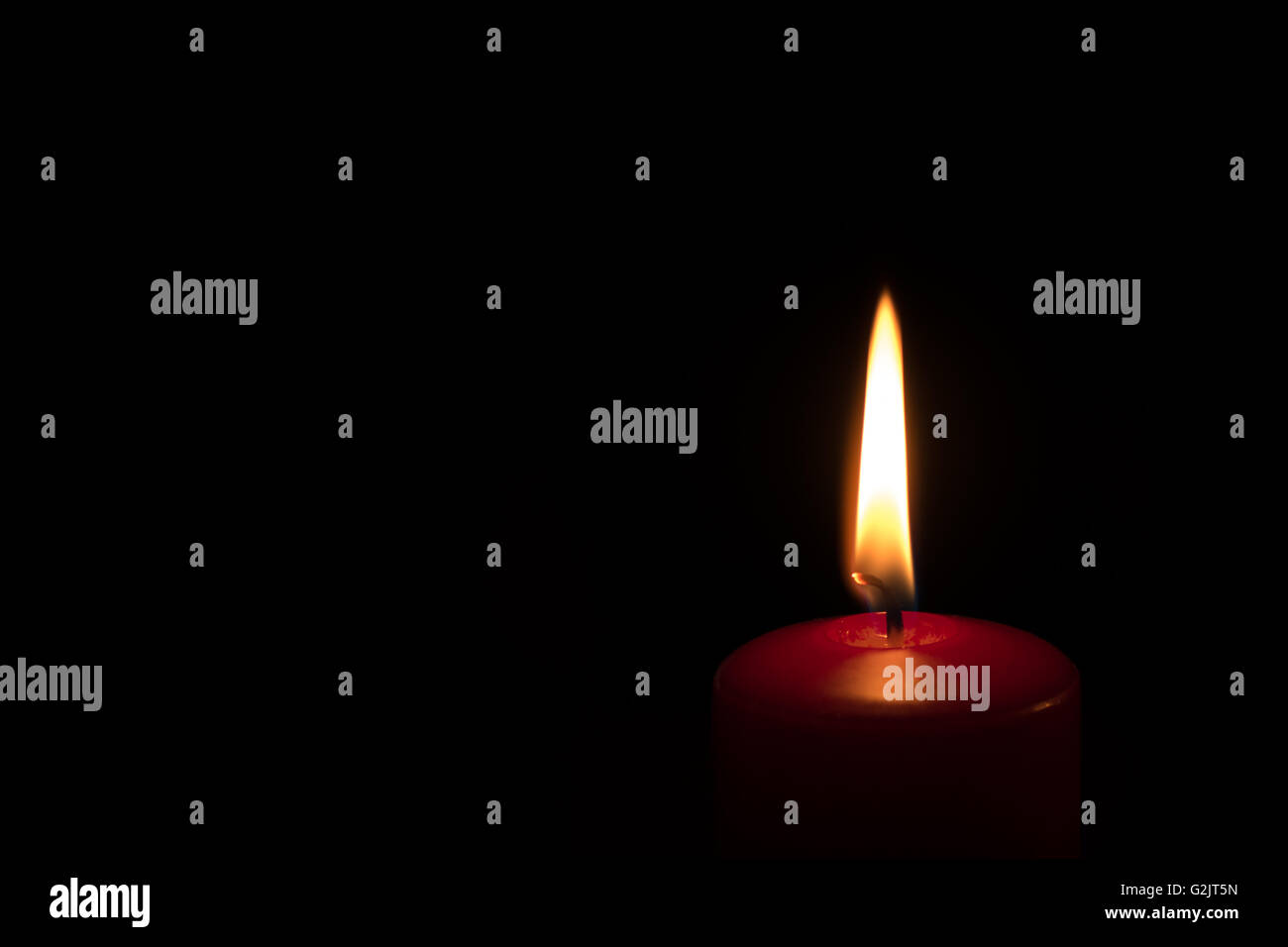 Burning red candle isolated on a black background with copy space. Stock Photo