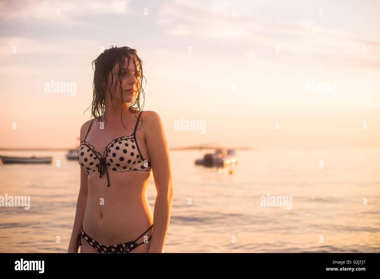 Beautiful young woman in swimsuit standing by the sea Stock Photo