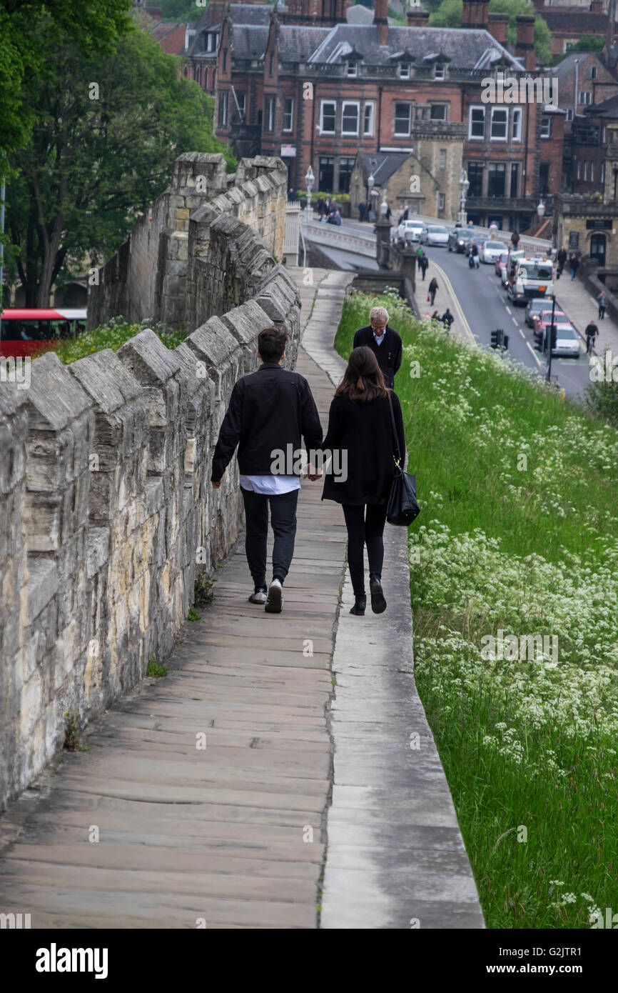 Young couple walk hand in hand along the old city walls of York Stock Photo