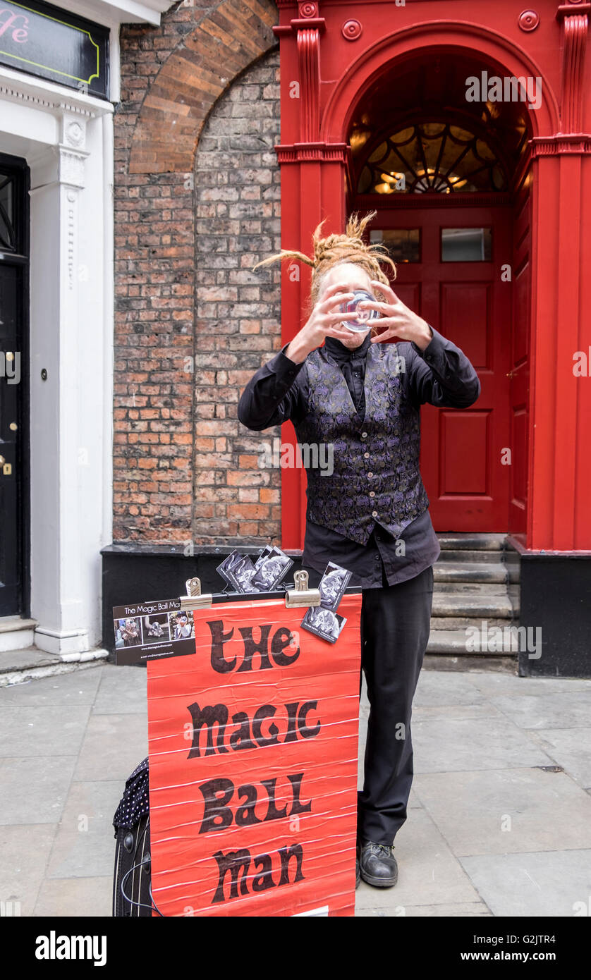 Street performer in York England dressed in black performing a magic ball trick. Stock Photo