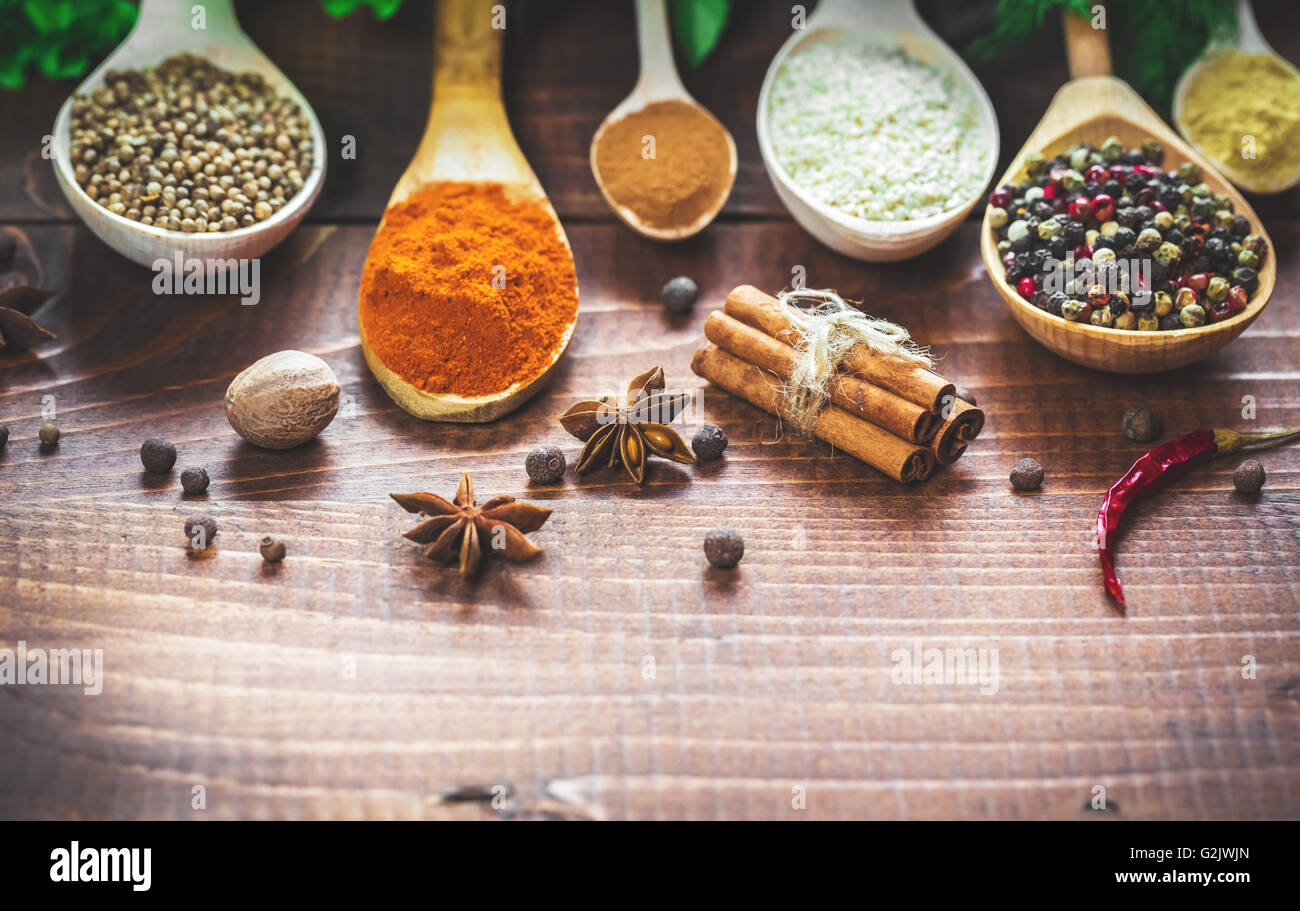 Beautiful colorful spices in wooden spoons and bowls on an old wooden brown table. Stock Photo
