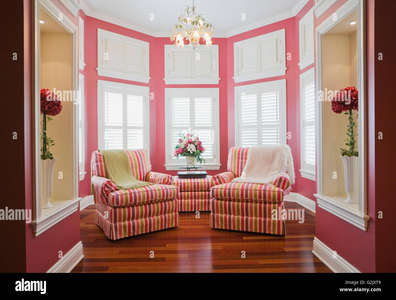 Pink green striped upholstered sitting chairs in alcove in master bedroom on upstairs floor inside elegant cottage style home Stock Photo