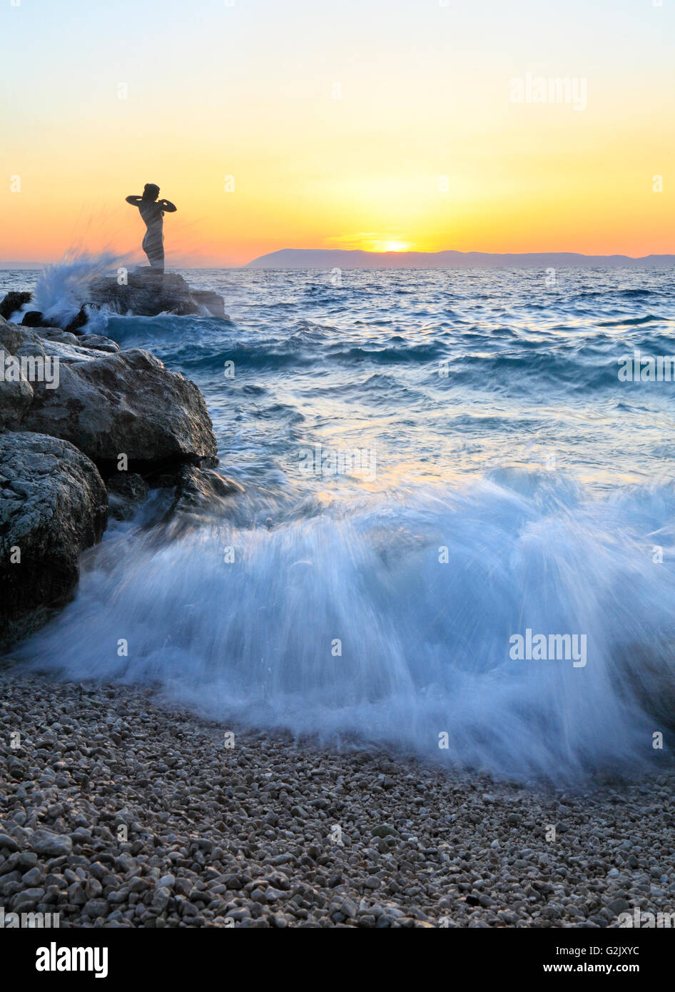 Statue of a woman on the rock at sunset in Podgora, Makarska Riviera, Croatia Stock Photo