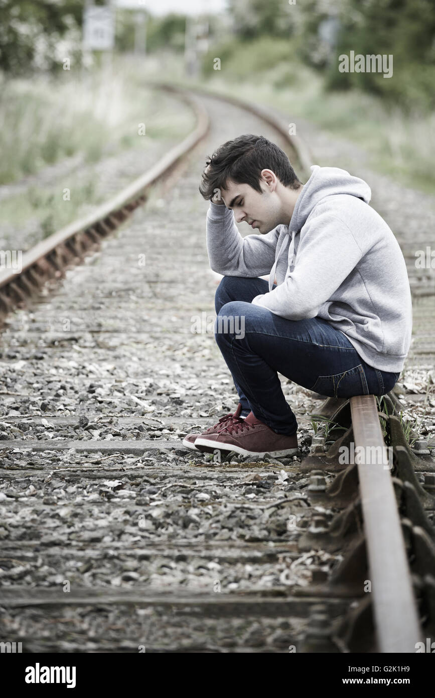 Depressed Young Man Sitting On Railway Track Stock Photo