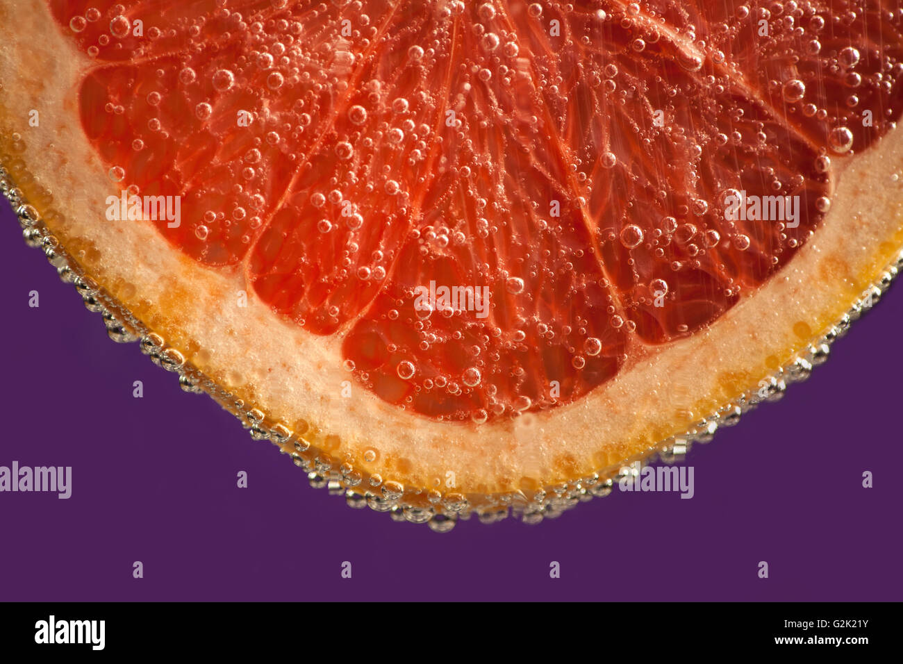 Grapefruit with fizzy bubbles on purple background Stock Photo