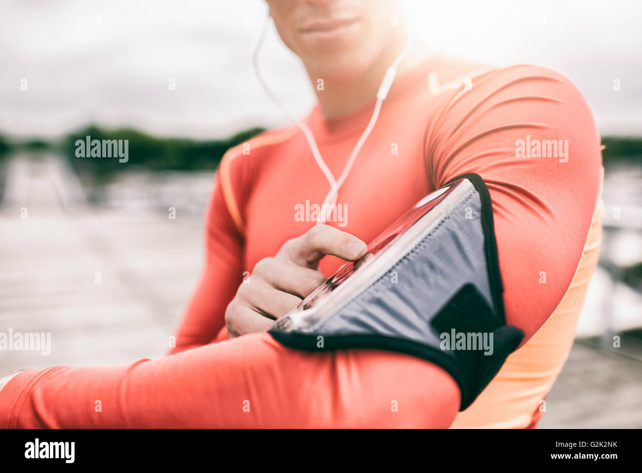 Outdoor runner man tuning his mp3 music player during jogging. Lens flare Stock Photo