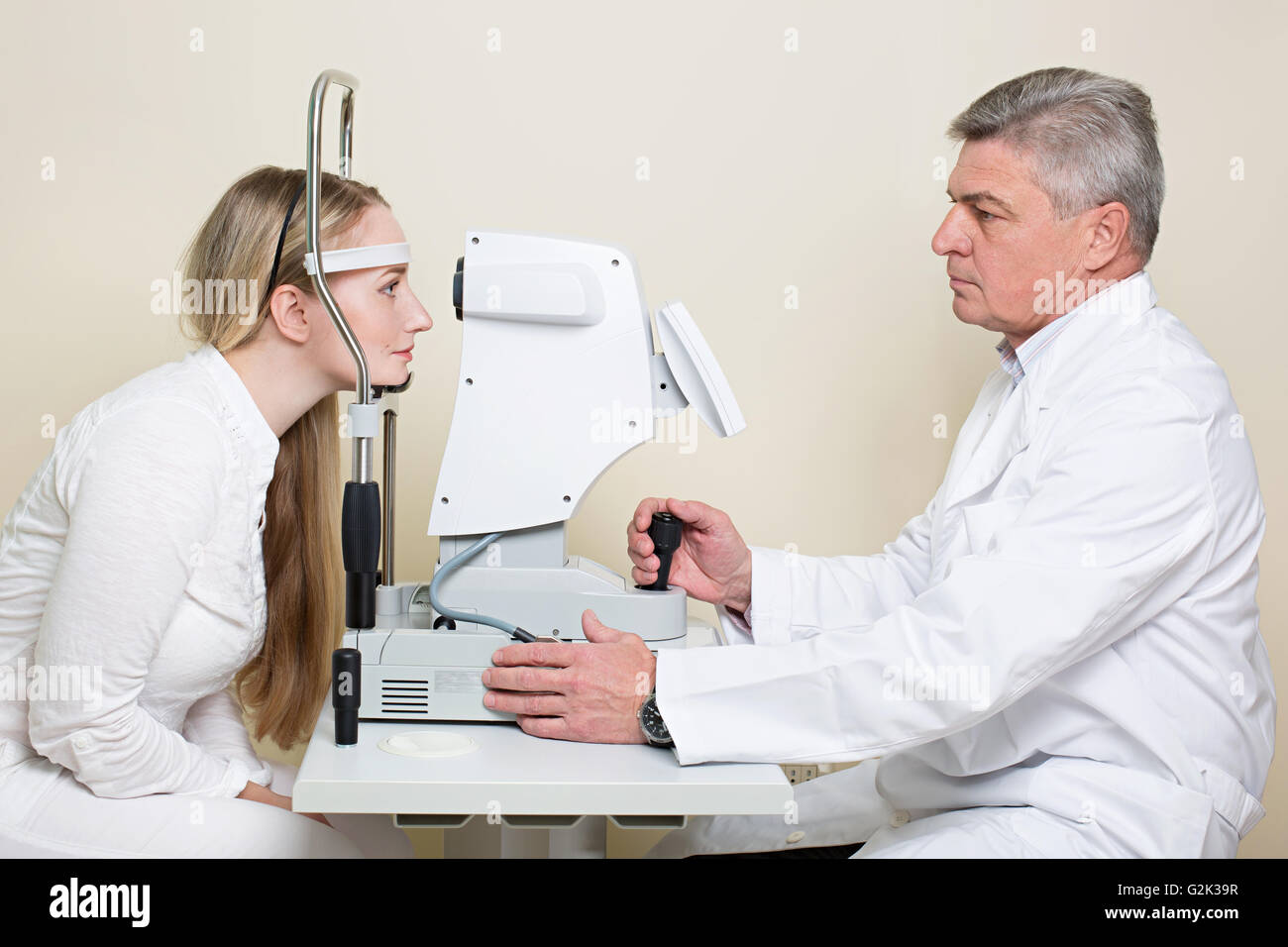 Young woman having her eyes examined by an eye handsome elderly doctor Stock Photo