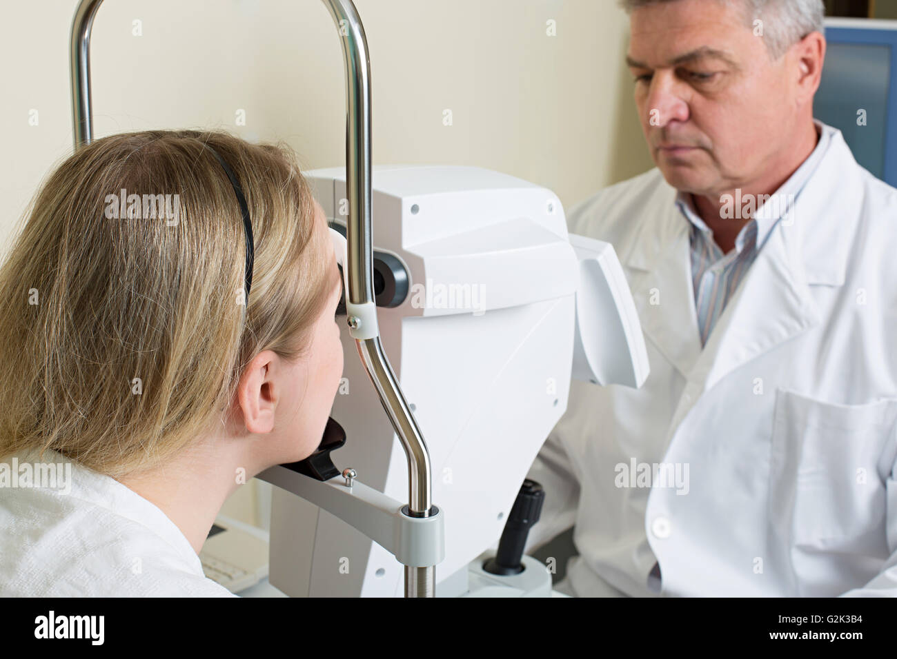 Young woman having her eyes examined by an eye handsome elderly doctor Stock Photo