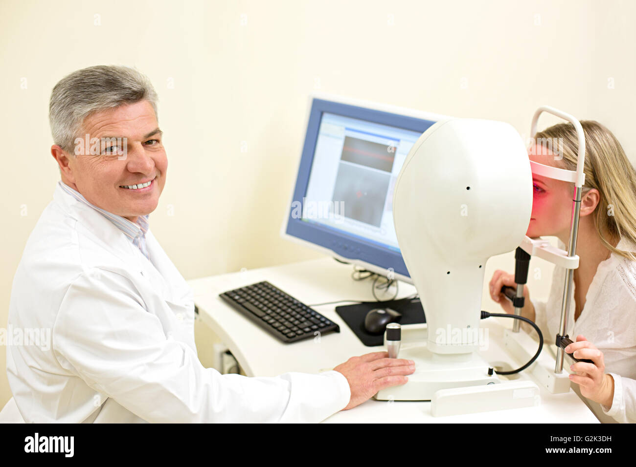 Young woman having her eyes examined by an eye handsome elderly doctor Stock Photo