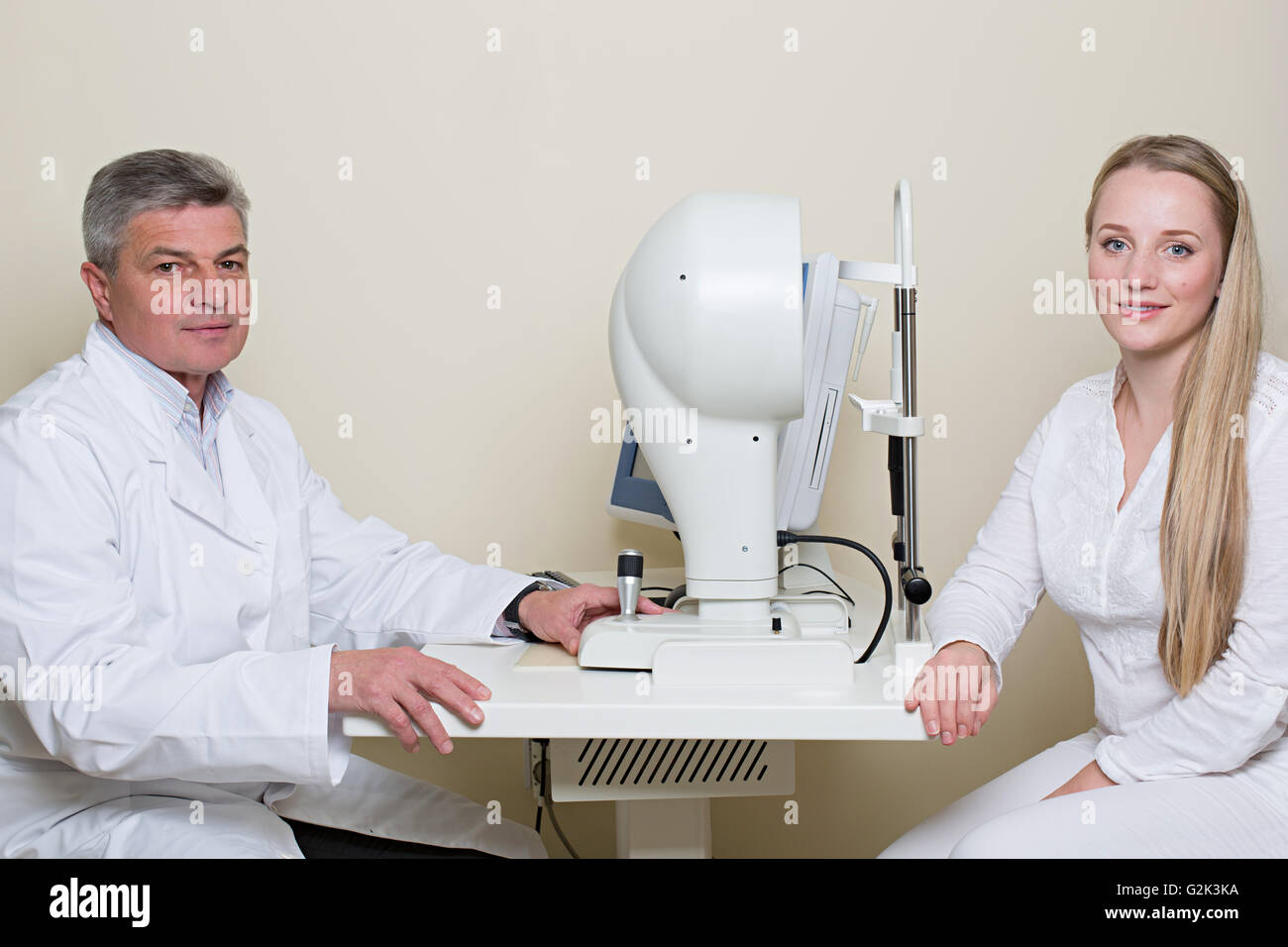 Young woman having her eyes examined by an eye handsome elderly doctor. Stock Photo