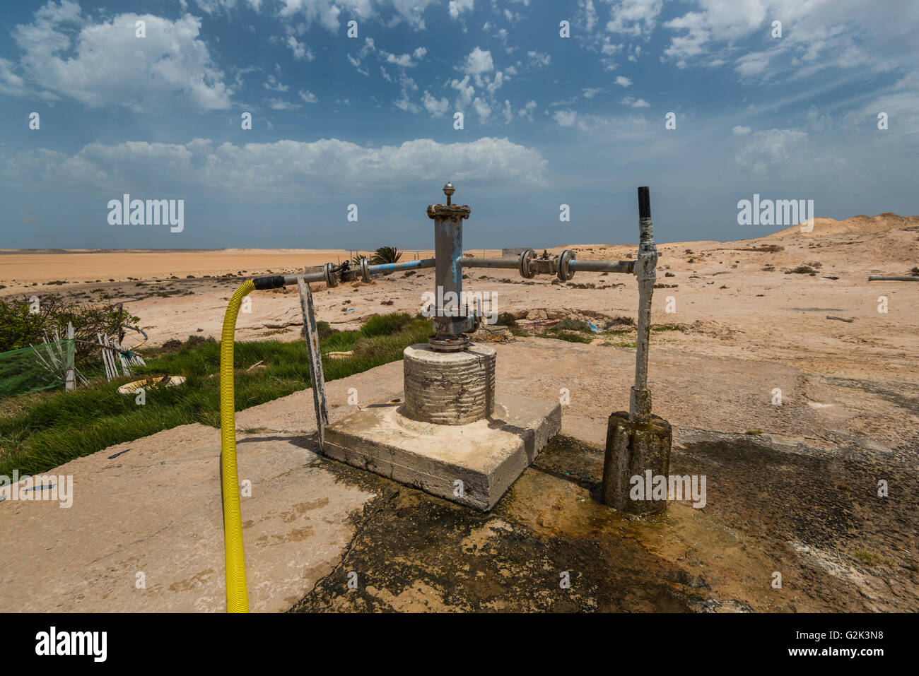 Water well in sandy desert with blue cloudy sky Stock Photo